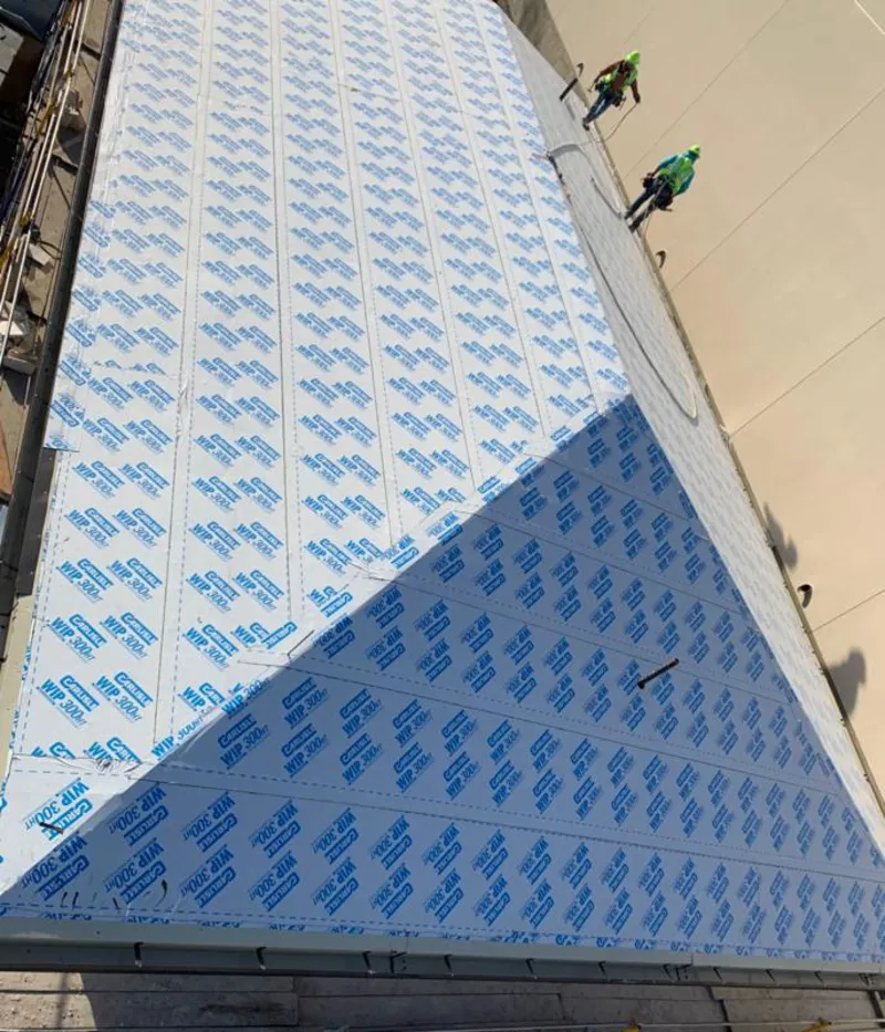 Professional roofers installing underlayment on a metal roof in Ashwaubenon